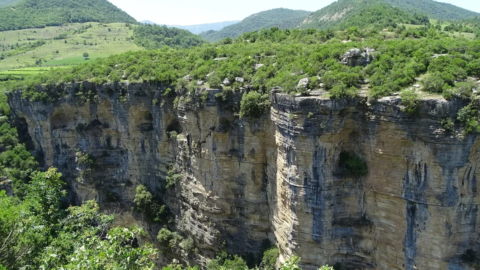 Layered limestone cliffs of Osumi Canyon dropping to the riverbed outside Corovode