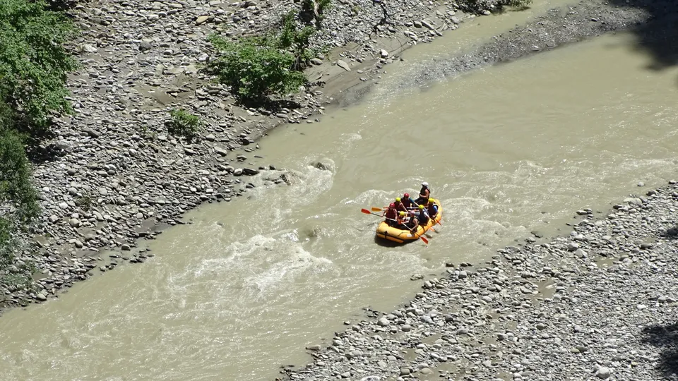 Rafters paddling an inflatable raft down a rapid between the limestone walls of Osumi Canyon